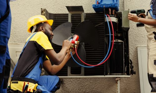 Worker refilling HVAC system refrigerant Proficient worker expertly refilling refrigerant in HVAC system while using barometer gauges to correctly measure the pressure in condenser, ensuring right cooling performance